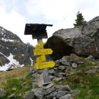 Wegweiser mit Felsunterstand im Hintergrund